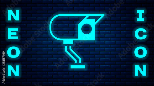 Glowing neon Security camera icon isolated on brick wall background. Vector.
