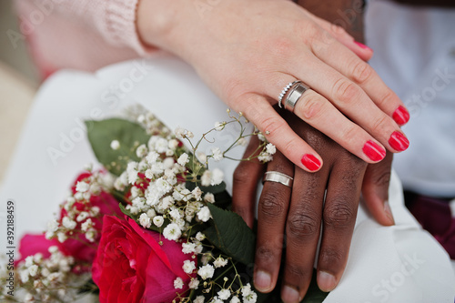 Happy multiethnic couple in love story. Relationships of african man and white european woman. Hands with rings. photo