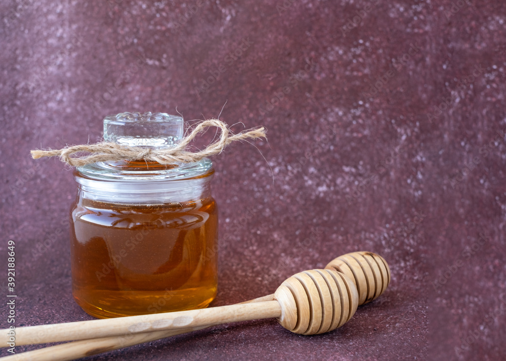 glass jar with honey on a Burgundy background glass jar with honey on a Burgundy background