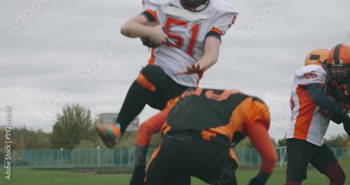 American football, football team in the game, training aggressive opposition during the game, the man breaks through with the ball in his hands and falls to the ground, 4k slow motion.