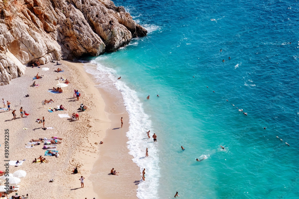 View of the turquoise beach. Beautiful Kaputas Beach (Turkey) with people resting under the sun and in the sea