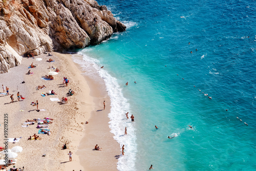 Fototapeta Naklejka Na Ścianę i Meble -  View of the turquoise beach. Beautiful Kaputas Beach (Turkey) with people resting under the sun and in the sea