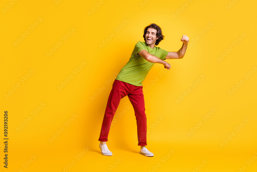 Full length body size photo of careless playful man wearing red trousers dancing laughing isolated on vivid yellow color background Full length body size photo of careless playful man wearing red trousers dancing laughing isolated on vivid yellow color background