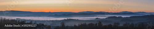 Fototapeta Naklejka Na Ścianę i Meble -  misty landscape at sunset, mountains rising from clouds of fog in the background, clear sky