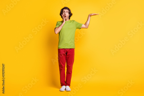 Full length body size photo of amazed touching cheek man demonstrating height in casual clothes isolated vibrant yellow color background