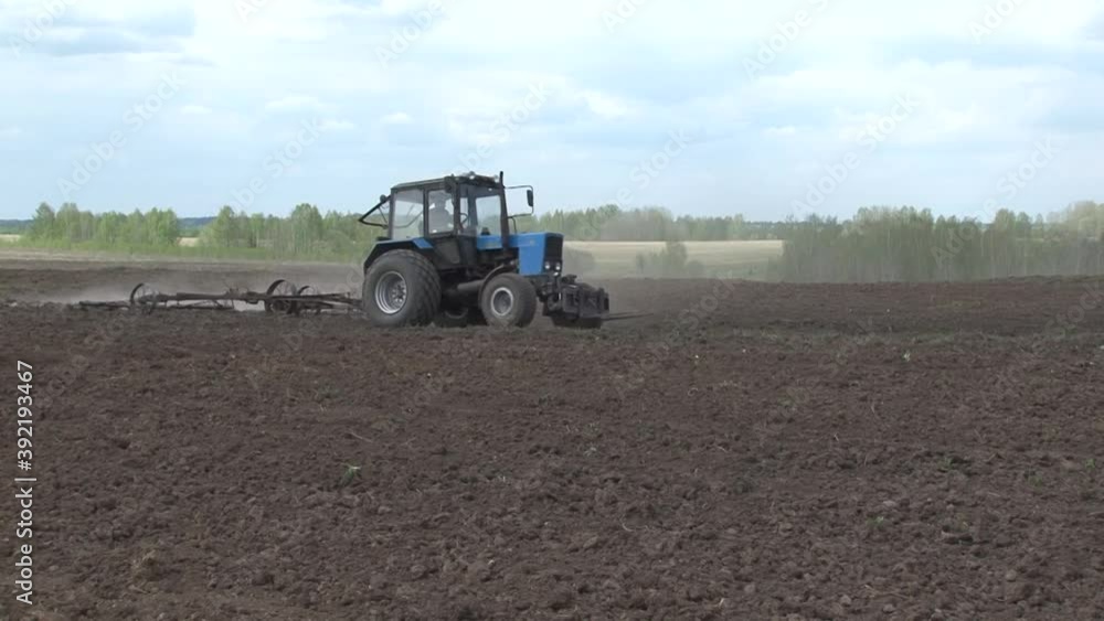 Harrowing a plowed field with a harrow and a tractor. Harrowing a plowed field with a harrow and a tractor.