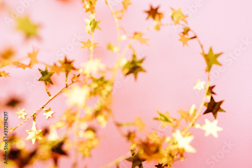Blurred Golden star sprinkles on pink. Festive holiday background. Celebration concept. Top view, flat lay. Horizontal