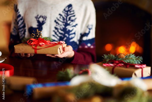  Men s hands hold Christmas present.  Man using red ribbon  green fir tree twig to create Christmas gift. Wintar holiday. 