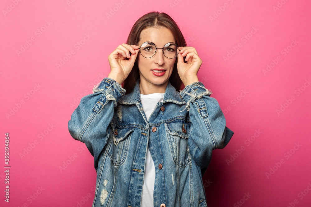 Beautiful young woman in round glasses and denim jacket on pink background. Beautiful young woman in round glasses and denim jacket on pink background.