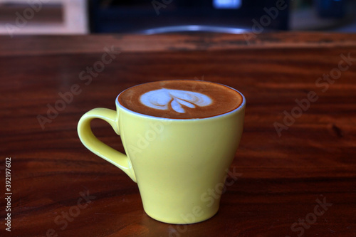 Drink scene of Hot Latt Coffee in yellow Cup on Brown wood Table at Coffee Cafe in Danang Vietnam
