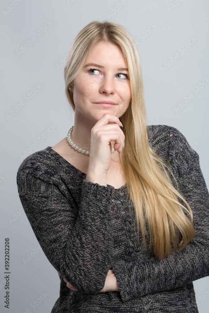 young blonde woman with hand at her chin is thinking about a problem young blonde woman with hand at her chin is thinking about a problem
