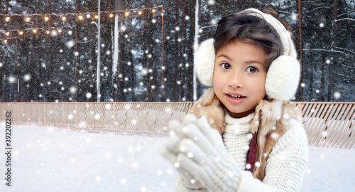 Принти на полотні christmas, season and children concept - happy little girl wearing earmuffs over