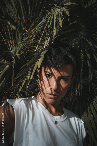 Portrait of a serious woman looking at the camera with green leaves in the background