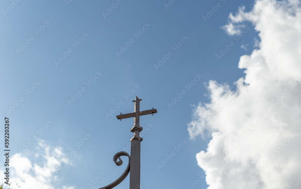 Metal cross located on the perimeter of a religious cemetery, on a sunny day Metal cross located on the perimeter of a religious cemetery, on a sunny day