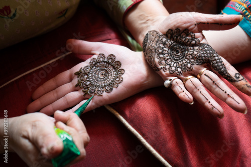 Top down video of a woman copying the mehndi henna tattoo from one hand to the other in preparation of the hindu festival of teej, karwachauth, diwali dussera or a marriage function photo