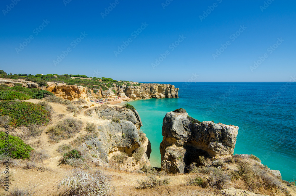 Beautiful rocky coastline with yellow limestone cliffs and blue Atlantic ocean. District Faro, Algarve, Southern Portugal
