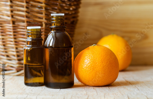 Small bottle with mandarin orange essential oil (clementine extract, tincture, infusion, perfume). Aromatherapy, spa and herbal medicine ingredients.Wooden background. Copy space