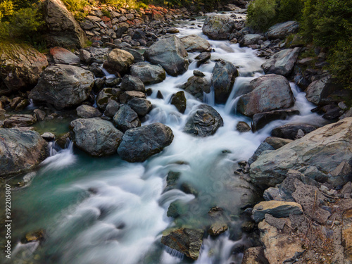 Aerial long exposure of alpine river in the mountain, silk effect, flowing water 