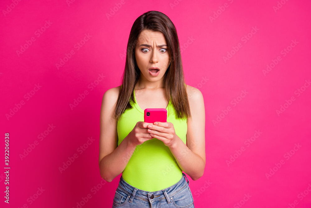 Photo of puzzled scared young girl hold smartphone confused look wear green top isolated bright pink color background Photo of puzzled scared young girl hold smartphone confused look wear green top isolated bright pink color background