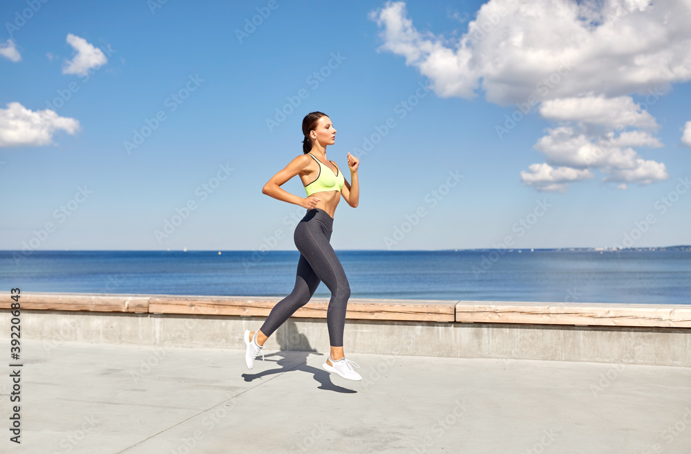 fitness, sport and healthy lifestyle concept - young woman running along sea promenade fitness, sport and healthy lifestyle concept - young woman running along sea promenade