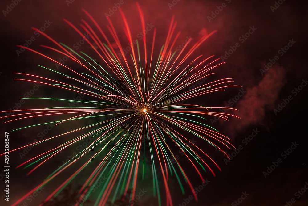 Fototapeta premium Brilliant red and green fireworks against the backdrop of the night sky, Vittorio Veneto, Italy