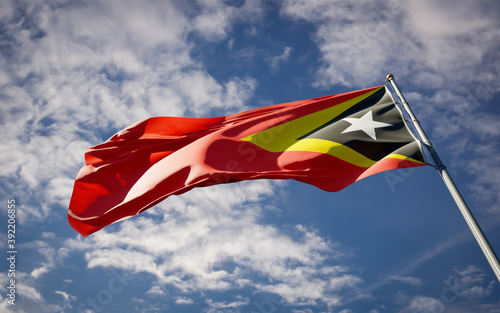 Beautiful national state flag of East Timor fluttering at sky background. Low angle close-up East Timor