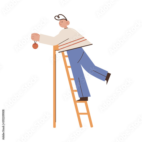 Boy standing on ladder and decorating Christmas tree with golden ball