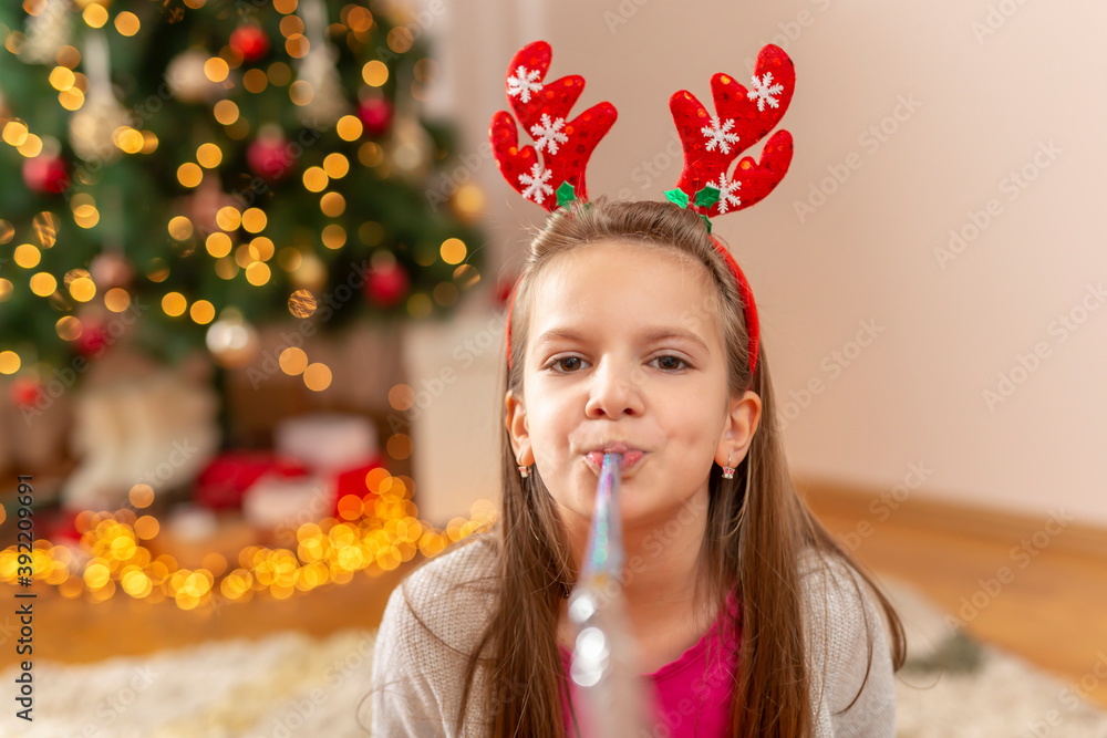 Little girl blowing party whistle on Christmas day
