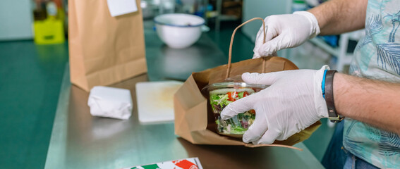 Unrecognizable cook packing a takeaway food order in the kitchen