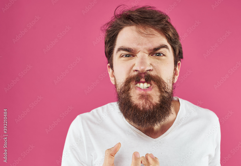 An angry man with a bushy beard bared his teeth against a pink background An angry man with a bushy beard bared his teeth against a pink background