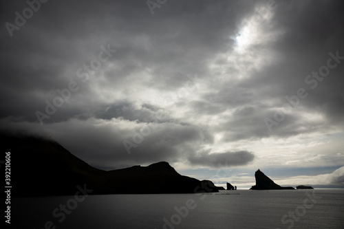 Tindholmur boulder peak against dark cloudy sky  backlit