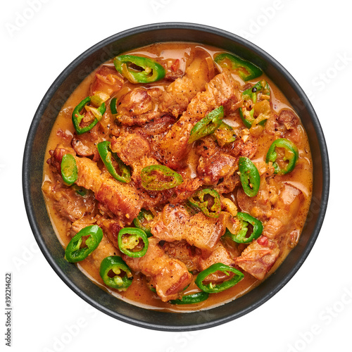 Bicol Express Stew in black bowl isolated on white. Filipino cuisine spicy pork belly coconut milk curry. Asian food.