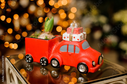 ceramic pot in form of red car with trailer in which bulbous plant grows