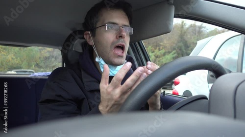 Stressed caucasian man screaming into car wearing protective mask. Angry man during coronaviurs pandemia. photo