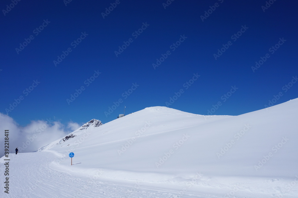 Winter landscape in the mountains. Snow-capped mountain peaks, blue sky, ski slopes.