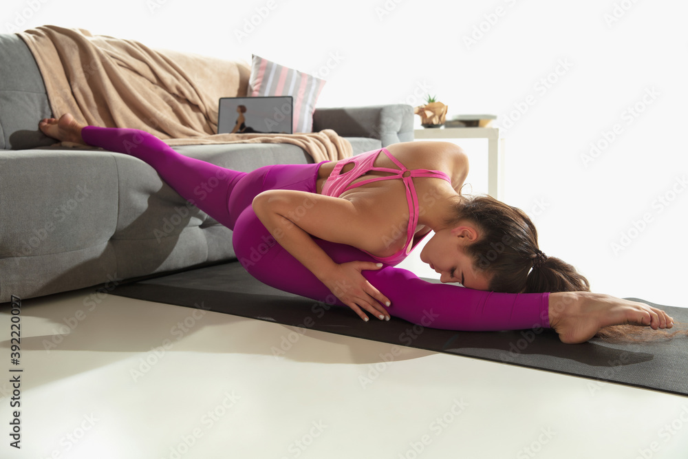 Stretching. Beautiful young woman working out indoors, doing yoga exercise on gray mat at home. Unrecognazible caucasian model practicing. Concept of healthy lifestyle, mental, mindfullness, balance. Stretching. Beautiful young woman working out indoors, doing yoga exercise on gray mat at home. Unrecognazible caucasian model practicing. Concept of healthy lifestyle, mental, mindfullness, balance.