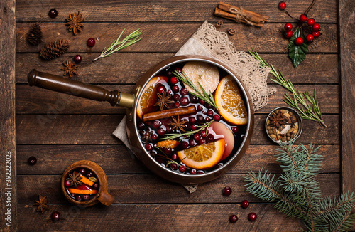 Christmas mulled red wine with the addition of spices and citrus fruits in a small vintage copper pan on a rustic wooden table, top view. Pot of mulled wine, traditional christmas drink.