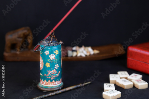 Antique opium pipe and other chinese objects (mahjong, incense stick and a red box) against black background photo