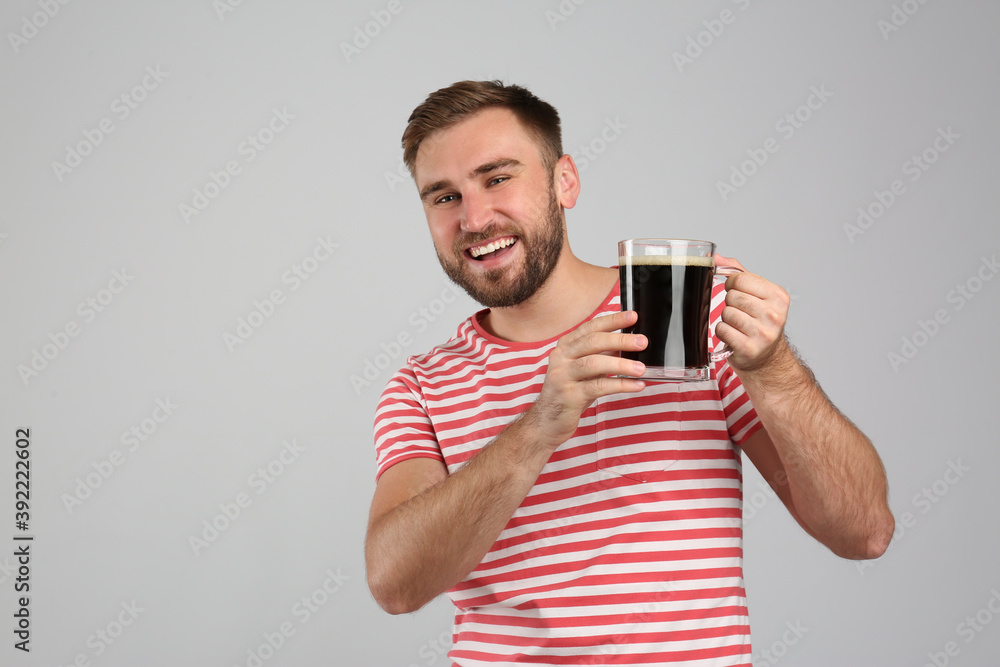 Handsome man with cold kvass on light grey background. Traditional Russian summer drink Handsome man with cold kvass on light grey background. Traditional Russian summer drink
