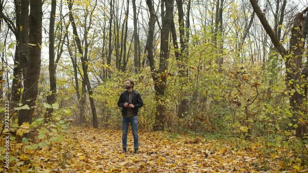 Conceived photographer walking in the autumn forest with a camera and photographing nature landscapes of golden autumn Conceived photographer walking in the autumn forest with a camera and photographing nature landscapes of golden autumn