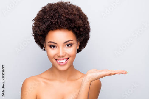 Close up photo of brown curly hair afro american girl hold hand show beauty skin care spa object recommend wellness pure fresh tone foundation gel isolated over grey color background