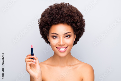 Close-up portrait of nice attractive charming cheerful wavy-haired girl with clean clear shine skin holding in hands new product natural lip balm isolated on light white gray color pastel background