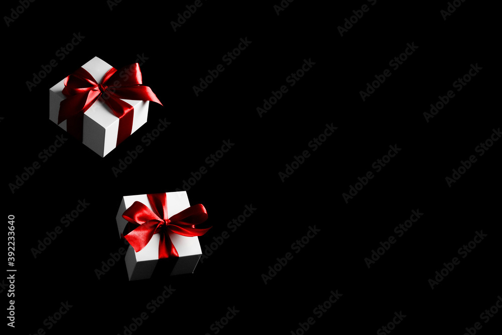 Black friday star. White gift box with red ribbon isolated on black background in Black Friday concept. Winter flying composition with copy space. Black friday star. White gift box with red ribbon isolated on black background in Black Friday concept. Winter flying composition with copy space.
