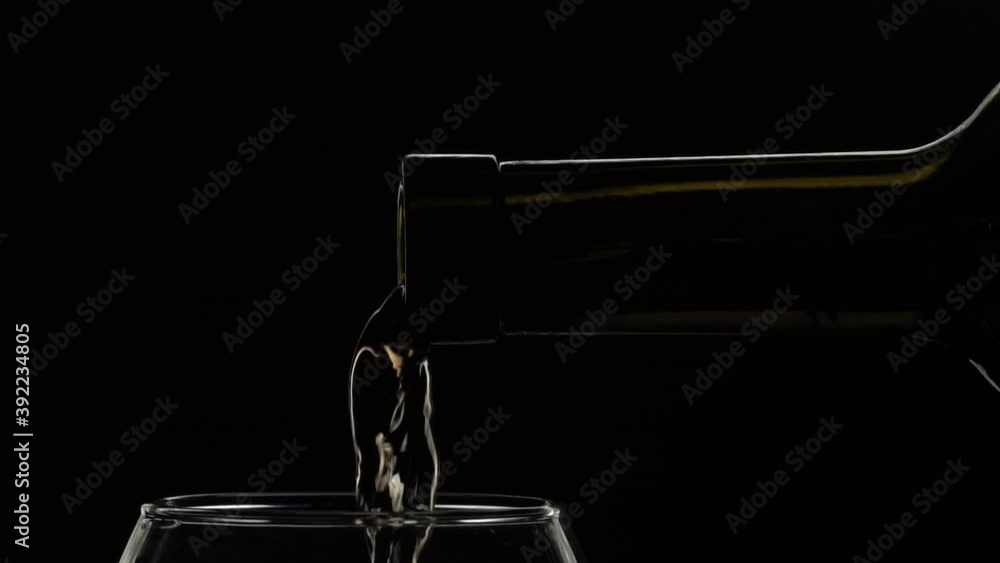 Young white wine pouring from bottle into glass. Smoke background slow motion. Low key light. Close up shot Young white wine pouring from bottle into glass. Smoke background slow motion. Low key light. Close up shot