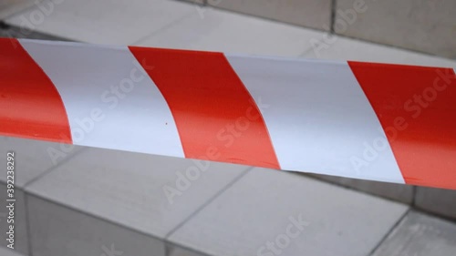 Red-and-white warning tape marks off an unsafe route, background