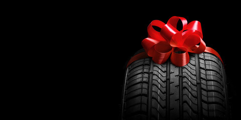 a  black isolation rubber tire, on the grey backgrounds in a bow for christmas