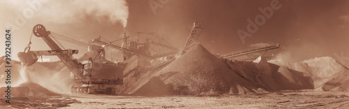 Excavator on the background of stone-crushing equipment at the limestone quarry, monochrome panoramic image of a light brown color, sepia. Mining industry.