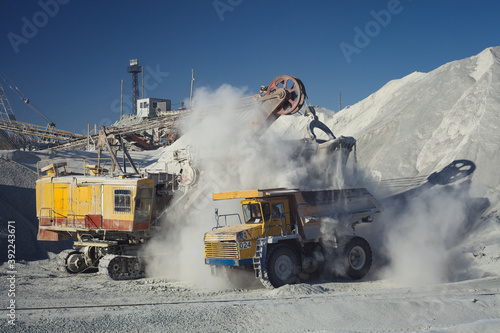 Loading excavator heavy mining truck at the limestone quarry. Mining industry.