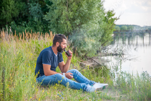 Stylish smoker smoking an vape outdoorr. Handsome man. photo