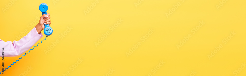 cropped view of african american woman holding blue retro phone on yellow, banner - obrazy, fototapety, plakaty 